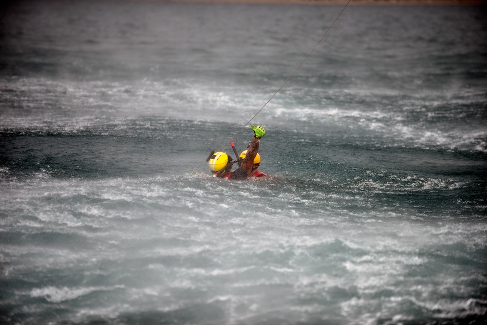 Coast Guard rescue swimmer signals helicopter during mock rescue