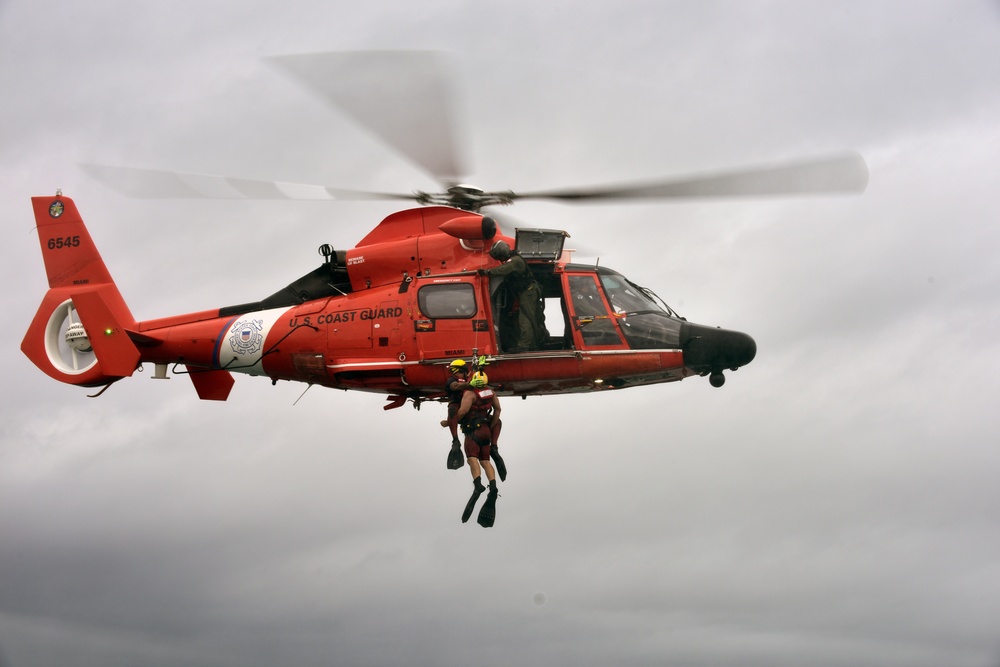 Coast Guard rescue swimmer and Jim Cantore hoisted by helicopter off Miami Beach