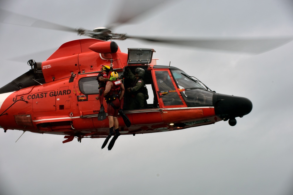 Coast Guard rescue swimmer and Jim Cantore hoisted by helicopter