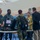 170615-N-SD711-0149 The image shows a group of military personnel in U.S. Navy digital camouflage uniforms gathered around registration tables in what appears to be a gymnasium or indoor facility. They are interacting with civilians and what appears to be a Canadian Forces member, likely during a briefing, exercise, or administrative event. Equipment cases labeled 'REGISTRATION' are visible on the tables.