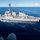 Bonhomme Richard Flight Operations A U.S. Navy Arleigh Burke-class guided-missile destroyer is underway at sea, photographed from an adjacent vessel during what appears to be an underway replenishment (UNREP) operation. The destroyer is sailing in calm, deep blue open ocean waters under partly cloudy skies. Crew members are visible on deck, and a transfer line or cable is visible connecting the two vessels.