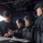 Sterett-Dewey Surface Action Group Deployment The image shows a group of military or law enforcement personnel gathered around a document or binder in what appears to be the interior of a naval vessel or military aircraft. One individual wearing a USS Sterrett (DDG-104) cap and black t-shirt is reviewing documents with three others wearing tactical helmets and body armor. The setting suggests a briefing or mission planning session.