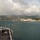 170614-N-LK571-076 A panoramic view from the flight deck of a U.S. Navy aircraft carrier in what appears to be Pearl Harbor, Hawaii. The flight deck is lined with naval personnel in white uniforms and packed with military aircraft. A rainbow is visible on the right side of the image over the harbor and surrounding cityscape.