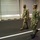 170615-N-NY430-0144 Two military personnel in different camouflage uniforms are walking together along a marked surface, likely inside a large facility or hangar. The individual on the left wears U.S. Army OCP (Operational Camouflage Pattern) uniform with tan boots, while the individual on the right wears U.S. Navy NWU Type III (green digital camouflage) uniform with black boots. Both wear patrol caps and appear to be conducting a walkthrough or inspection.