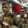 170614-N-GG458-052 A group of U.S. Marines in full combat gear with camouflage face paint are staged inside what appears to be a naval vessel. The lead Marine is wearing a tactical vest with visible name tape, blood type patch, and USMC Eagle Globe and Anchor insignia. The personnel appear to be preparing for or awaiting a combat or training operation.