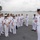 Sterett-Dewey Surface Action Group Deployment A group of naval personnel in white dress uniforms are gathered on the deck of a warship, appearing to be engaged in a formal briefing or exchange visit. A senior US Navy petty officer on the right is addressing a delegation of what appear to be Chinese People's Liberation Army Navy (PLAN) officers, with several US Navy sailors also present in the background. The setting suggests an official military-to-military exchange or port visit.
