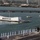 170614-N-LK571-149 U.S. Navy sailors in dress white uniforms are manning the rails of an aircraft carrier flight deck as it passes the USS Arizona Memorial at Pearl Harbor, Hawaii. The iconic white memorial structure is visible across the water with an American flag flying at its flagpole. This ceremonial formation is a traditional naval tribute rendered when passing a memorial or entering/departing a significant port.