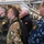 170614-N-JI086-354 A group of military personnel from multiple NATO nations are gathered inside what appears to be a naval vessel or military facility. Visible national insignia include German, Italian, and Polish flags on uniforms, along with a naval officer in blue digital camouflage. The group appears to be attending a briefing or tour, all facing the same direction.