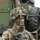 170614-N-PF515-014 A Polish Army soldier stands in full combat gear with camouflage face paint and a ghillie-covered helmet. He is holding a firearm and wearing the distinctive Polish 'Pantera' woodland camouflage uniform with a Polish flag patch visible on the left sleeve. A large military vehicle is visible in the background.