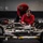 170613-N-TV230-004 Two individuals wearing red tops are working on what appears to be aircraft landing gear assemblies or similar wheeled mechanical equipment laid out on a hangar floor. The foreground person, a woman with her hair pulled back, is closely inspecting or adjusting components, while a second person is bent over working in the background. The setting appears to be a military or aviation maintenance facility.