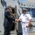170613-N-FM530-083 A civilian in a dark suit is shaking hands with a naval officer in white dress uniform on the deck of a military vessel. A third person in military camouflage uniform is visible in the background through an open hatch. The setting appears to be an official visit or ceremony aboard a warship.