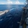 Bonhomme Richard Conducts Fueling at Sea with USS John S. McCain (DDG 56) Two naval vessels are conducting an underway replenishment (UNREP) operation at sea, with transfer lines and hoses visibly connecting the two ships. The image is taken from an elevated position on the receiving vessel looking across to the supply ship on the left. Personnel in safety gear are visible on both vessels' decks during this coordinated maritime logistics operation.
