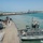 170614-N-FQ994-183 A naval port scene showing a large warship being assisted by a gray tugboat during a docking or undocking maneuver. Multiple naval vessels are visible in the harbor, including what appear to be Arleigh Burke-class destroyers in the background. The port infrastructure, including piers and shore facilities, is visible along the coastline.