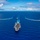 170612-N-BL637-083 An aerial photograph shows a naval carrier strike group underway on open ocean, with a large aircraft carrier in the foreground leading the formation. The carrier's flight deck is visibly populated with aircraft, and it is flanked by at least three escort vessels — likely guided-missile destroyers or cruisers — positioned to the port, starboard, and ahead. All vessels are generating visible white wakes, indicating active forward movement.