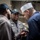 170612-N-MJ135-038 Three military personnel, appearing to be U.S. Navy sailors, are engaged in a conversation or briefing in what appears to be the interior of a naval vessel. The central figure, identified by a name tag reading 'JONES,' is wearing a gray uniform with rank insignia and a dark navy cap with gold lettering. A third sailor in a white dixie cup hat appears to be reviewing a document or device.
