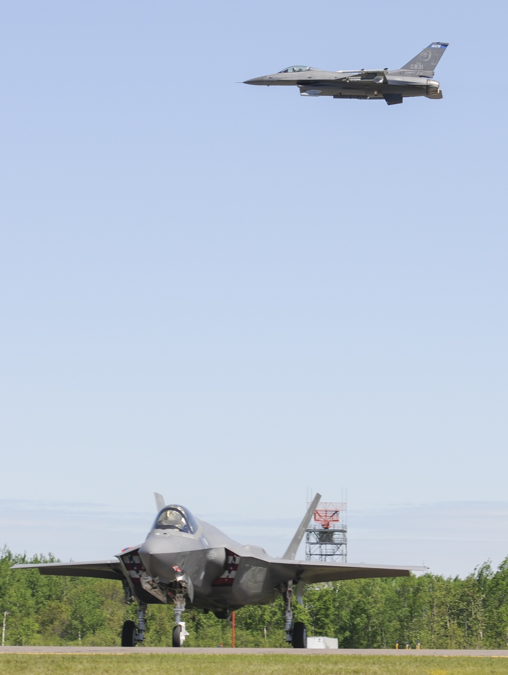 F-16 flies over the F-35