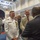 Marine Barracks Washington; EveningParade July 14, 2017 A formal military and civilian reception or networking event taking place in an ornate ballroom or ceremonial hall. A U.S. Navy officer in white dress uniform adorned with multiple medals and ribbons is engaged in conversation with civilians wearing business attire and conference lanyards. The setting suggests a high-level defense or government conference.