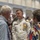 Marine Barracks Washington; EveningParade July 14, 2017 A high-ranking naval officer in formal white dress uniform adorned with numerous medals and ribbons is engaged in conversation with two civilians at what appears to be a formal reception or military social event. The setting is an elegant ballroom or event hall with classical architectural details. Multiple other attendees are visible in the background, suggesting a large gathering.
