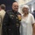 Marine Barracks Washington; EveningParade July 14, 2017 A high-ranking U.S. Marine Corps officer in dress blues uniform poses with a woman in a white lace outfit at what appears to be a formal military ceremony or reception. The officer displays numerous medals, ribbons, and gold buttons consistent with senior flag officer rank. The setting is an elegant indoor venue with arched architectural details and blue drapery.