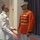Marine Barracks Washington; EveningParade July 14, 2017 Two military officers are engaged in conversation in what appears to be a formal indoor venue. One officer wears a white U.S. Navy dress uniform with gold shoulder boards and medal ribbons, while the other wears a distinctive red U.S. Marine Corps ceremonial dress uniform with gold braiding, aiguillettes, and a white peaked cap. The setting and attire suggest a formal military ceremony or official event.
