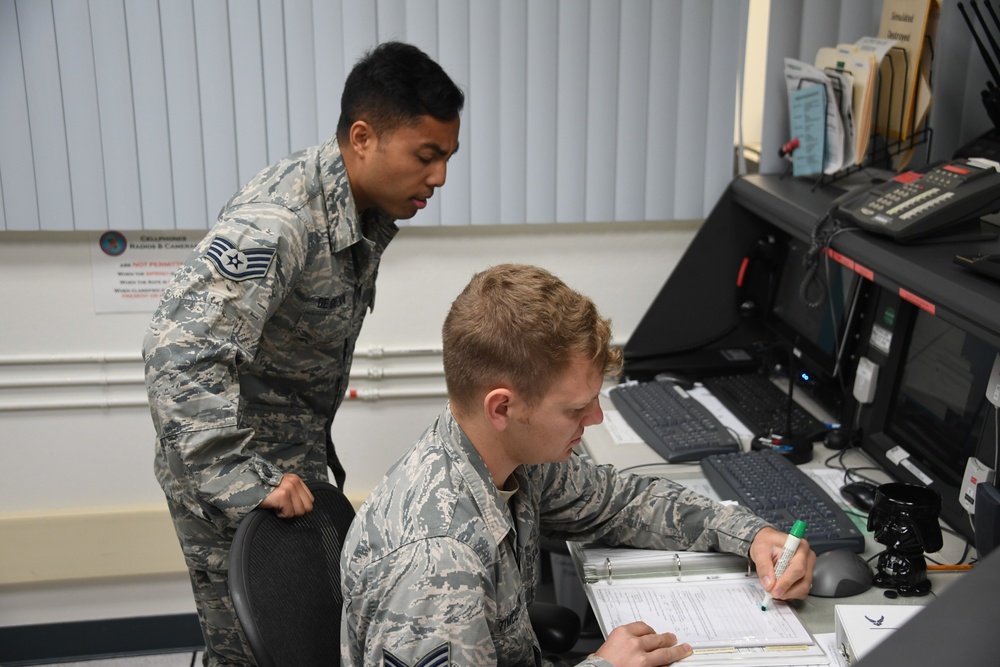 Staff Sgt. Andrew Tymczyszyn and Staff Sgt. Kevin De Guzman working in the 146AW Command Post