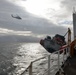 MH-60 Jayhawk helicopter transits above the Coast Guard Cutter Healy
