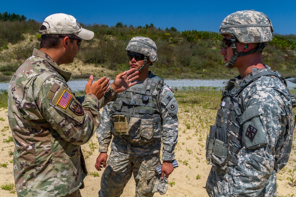 Sgt. Joseph Hall teaches Spc. Kenny Ochoa and Spc. Wantea Seong techniques with the M4 rifle