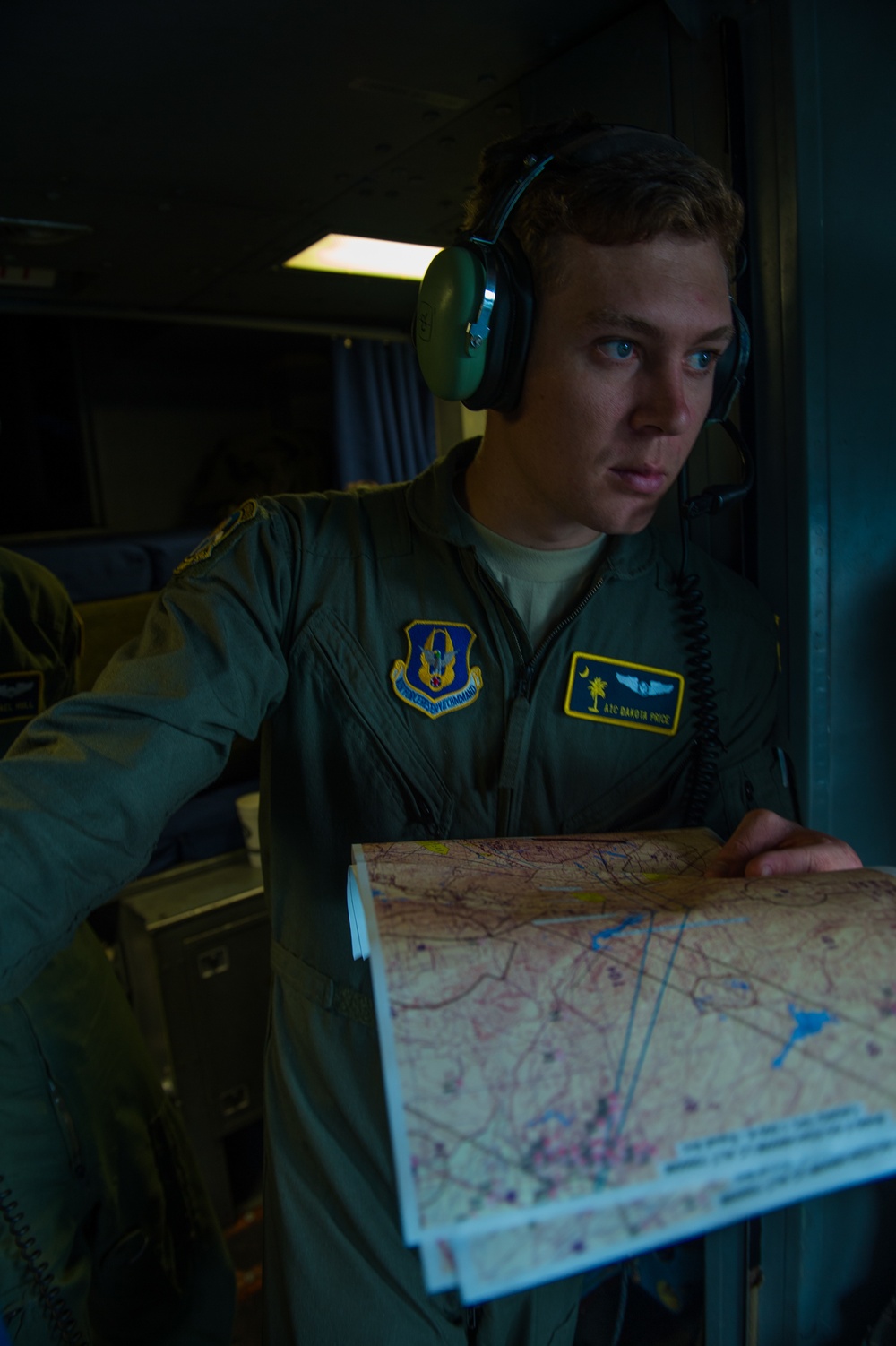 USAF-R C-17 loadmaster A1C Dakota Price assists pilot in chart navigaion