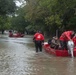 A Coast Guard Flood Punt Team transports a man across a flooded neighborhood