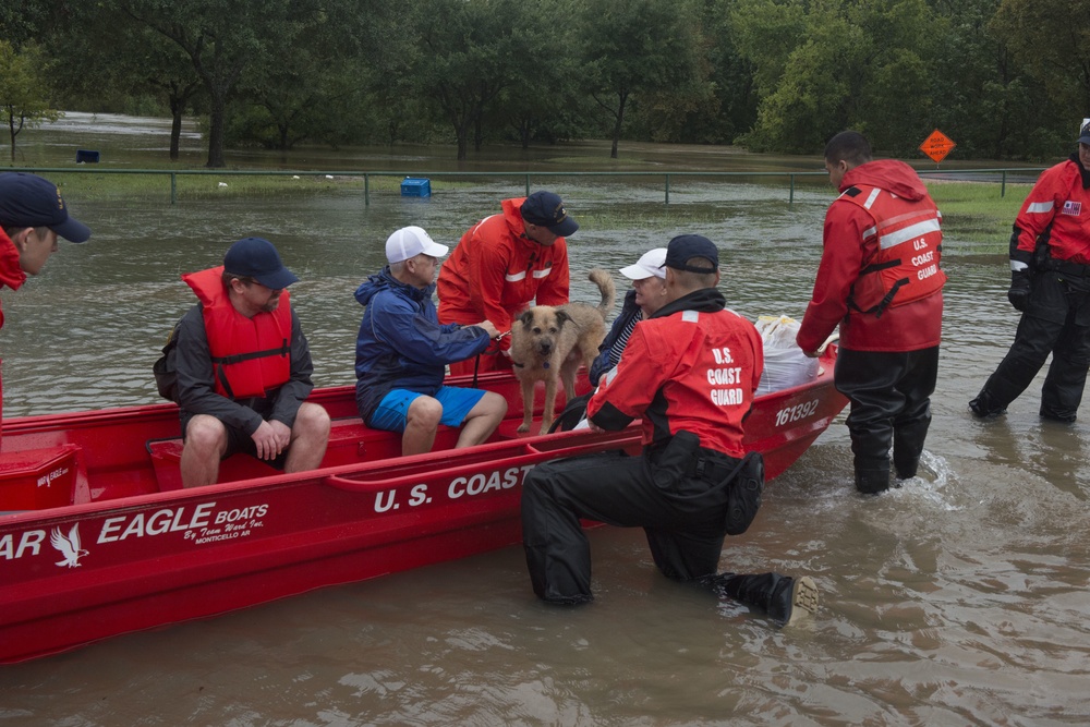 A Coast Guard Flood Punt Team transports a family and their dog through a flooded neighborhood