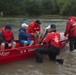 A Coast Guard Flood Punt Team transports a family and their dog through a flooded neighborhood