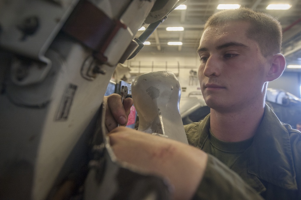 Sailors and Marines aboard the amphibious assault ship USS America (LHA 6) conduct maintenance in the ship’s hangar bay