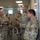 Hurricane Harvey Response A group of U.S. Army personnel in Operational Camouflage Pattern (OCP) and Army Combat Uniform (ACU) uniforms are gathered in what appears to be a military office or operations center. One soldier on the right is gesturing with his hand, appearing to brief or instruct the group. The setting suggests an official military briefing or facility tour.