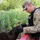 A U.S. Army soldier in Operational Camouflage Pattern (OCP) uniform is interacting with a dark brown dog, likely a military working dog (MWD). The soldier is leaning forward and appears to be rewarding or bonding with the dog in an outdoor training environment. A name tape reading 'US ARMY' and a partial surname are visible on the uniform.
