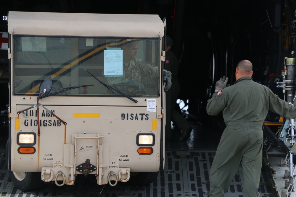 Soldier guiding a driver of a SATS vehicle as he loads it into a C-5M Super Galaxy.