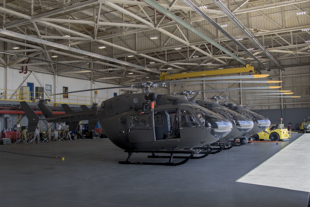Soldiers move the blades of three UH-72 Lakota helicopters in together to make more space for other aircraft.