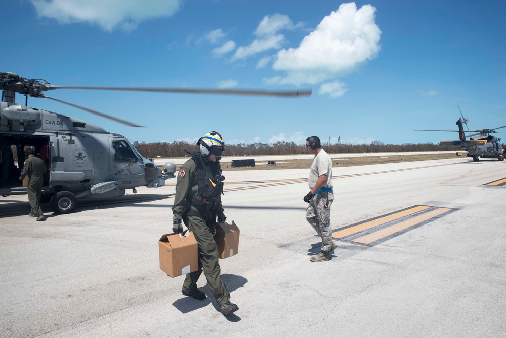 Air Crewman (Helicopter) 2nd Class Kurt Weber, from Langing, Kansas, drops off water from an MH-60R Sea Hawk, from the Spartans of Helicopter Sea Maritime Squadron (HSM) 70