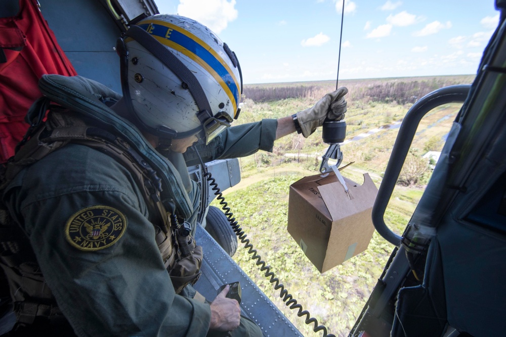 Air Crewman (Helicopter) 2nd Class Sam Jeune, from Grand Rapids, Minnesota, prepares to lower water to residents affected by Hurricane Irma from an MH-60R Sea Hawk