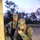 Preparing for a Disaster on Kauai Two U.S. Army soldiers in Operational Camouflage Pattern (OCP) uniforms are working at dusk near a structure. The foreground soldier is speaking into a handheld radio while reviewing a Dell laptop computer placed on a ledge. The background soldier, wearing captain's rank insignia, observes the activity.