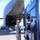 Utah's 85th CST load equipment on a C-17 to return from Kauai A military service member in camouflage uniform and olive t-shirt stands on a tarmac reviewing documents next to a dark blue emergency/fire vehicle. Behind him, a large military cargo aircraft (likely a C-17 Globemaster III) has its rear cargo ramp open and lowered. The scene appears to depict a cargo offload or inspection operation at an airfield.