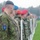 A military formation featuring soldiers from multiple nations standing in a line during what appears to be a formal ceremony or parade. The foreground soldier clearly displays Lithuanian military insignia, including a 'LITHUANIA' tab, the Lithuanian flag patch, and a 'LITPOLUKRBRIG' (Lithuanian-Polish-Ukrainian Brigade) shield patch. Soldiers are wearing various beret colors including black, red, blue, and green, indicating different units or nationalities.