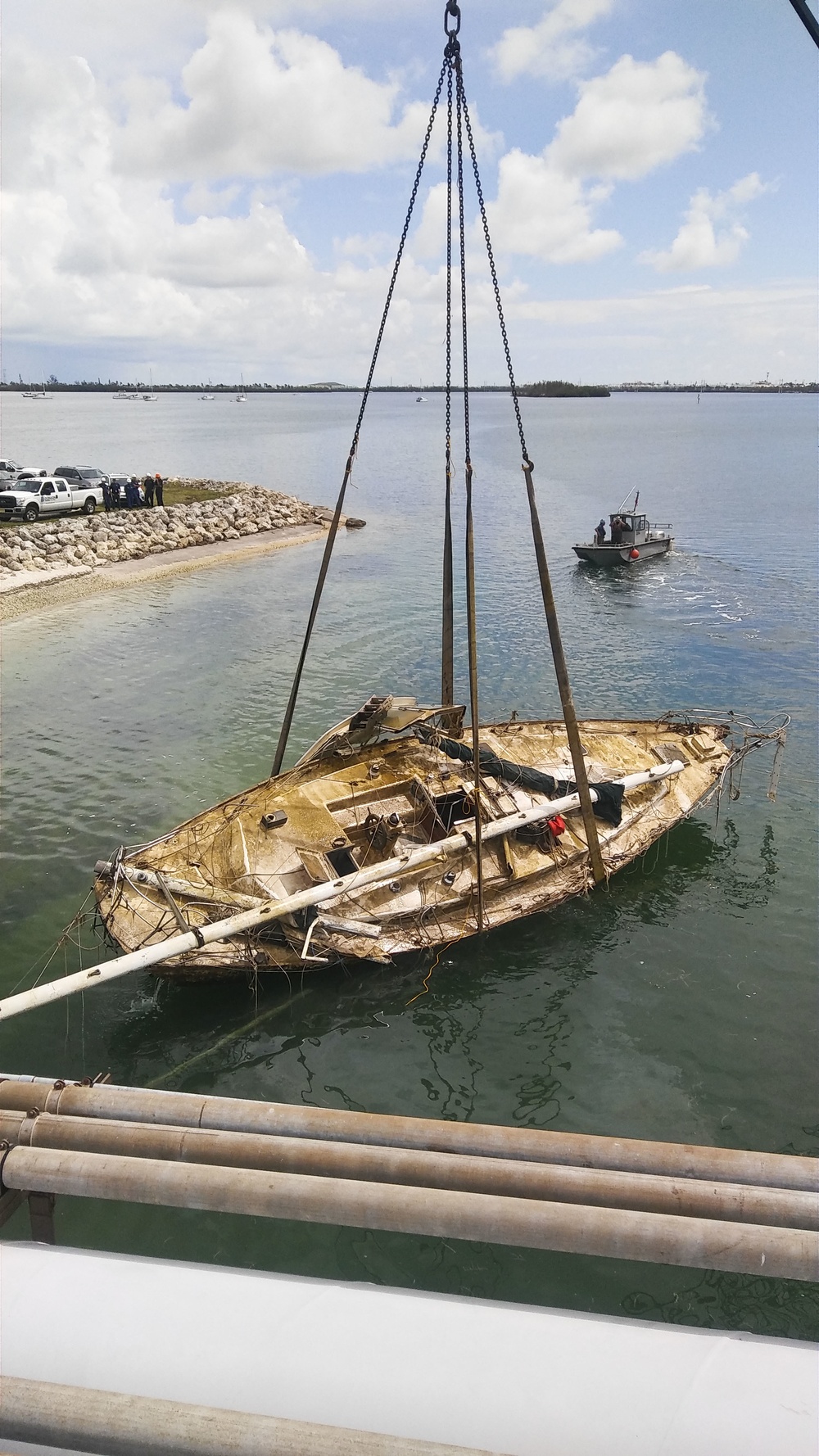 Response crews facilitate the hoist of a sailboat displaced by Hurricane Irma