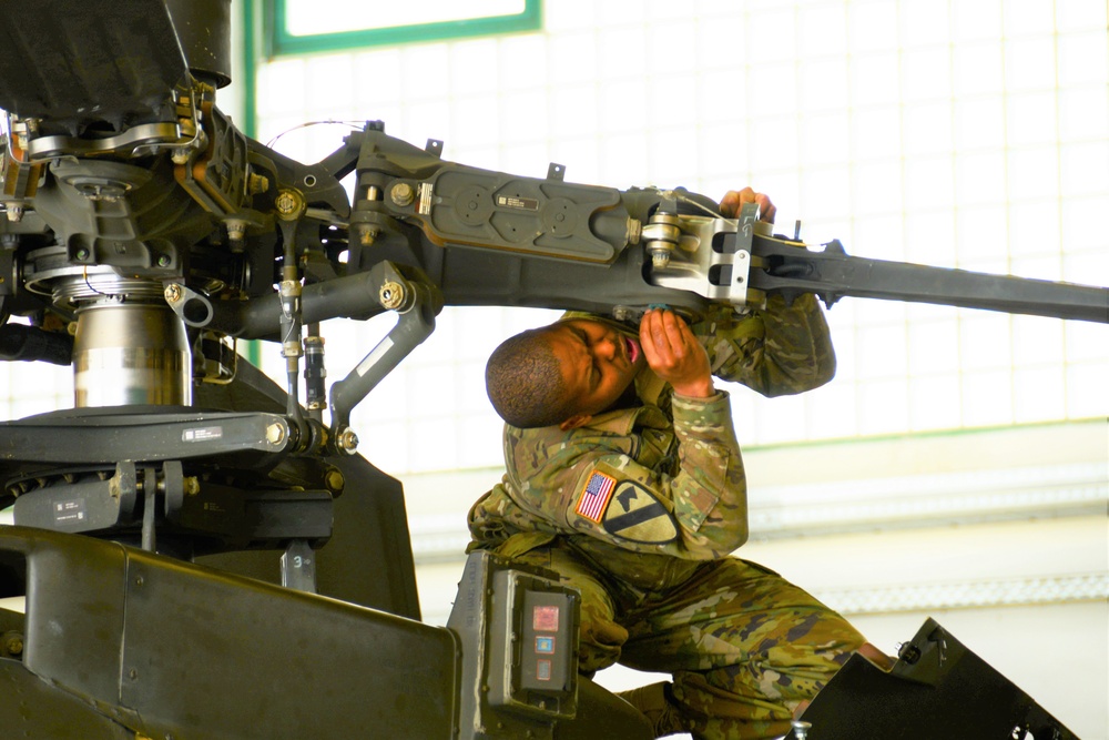 Soldier working on  rotor blade of Apache.