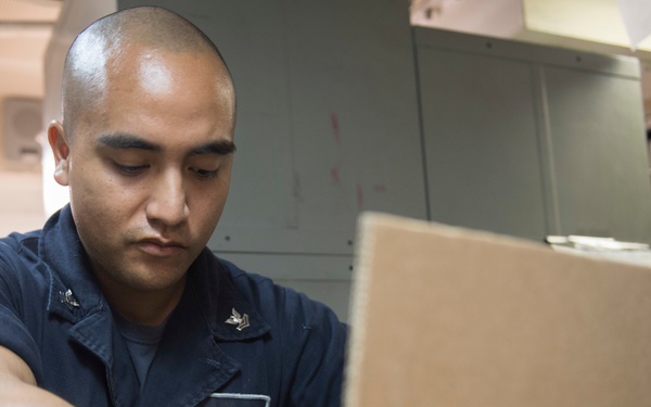 USS Lake Erie (CG 70) Sailors unpacks shipment