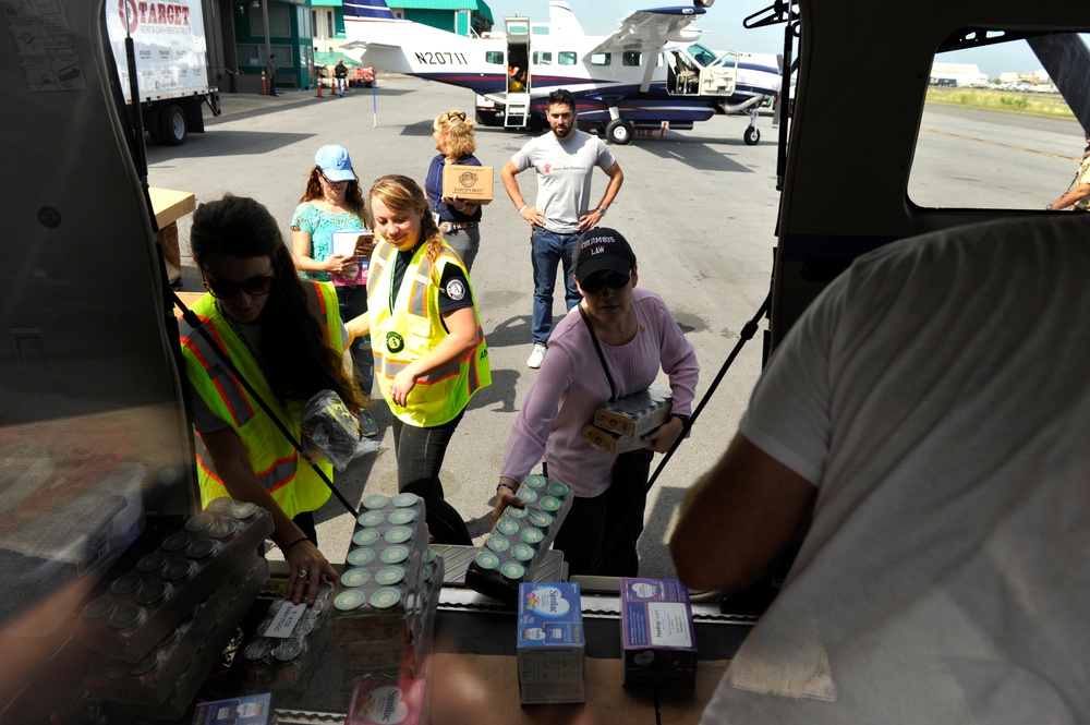 Secretary of the Puerto Rico Department of Family, federal workers, and volunteers prepare infant goods for distribution to families in need