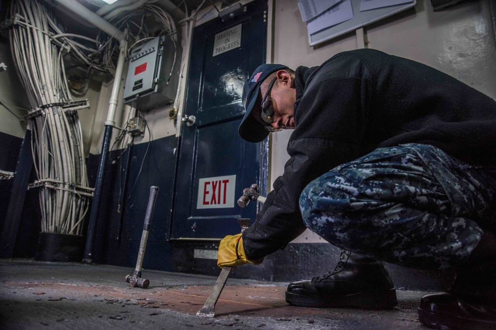 Sailor removes non-skid from the deck.