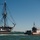A large historic tall ship decorated with colorful signal flags and pennants sails alongside a U.S. Coast Guard patrol boat on open water under a clear blue sky. The tall ship appears to be a classic wooden sailing vessel with multiple masts and elaborate rigging, consistent with an 18th or 19th century warship or replica. The Coast Guard vessel appears to be providing escort or security during what looks like a public sailing event.