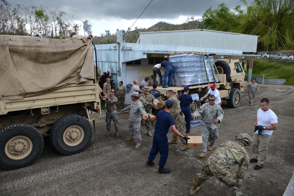 Coast Guard Investigative Service and Army personnel deliver aid to residents of Puerto Rican neighborhoods