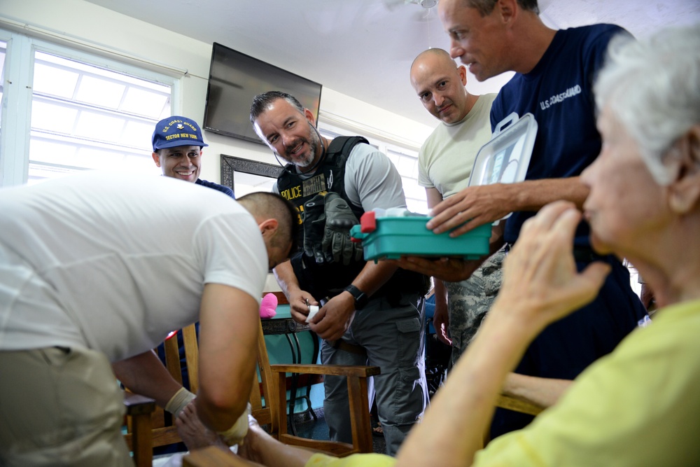 Coast Guard Investigative Service and Army personnel deliver aid to residents of Puerto Rican neighborhoods