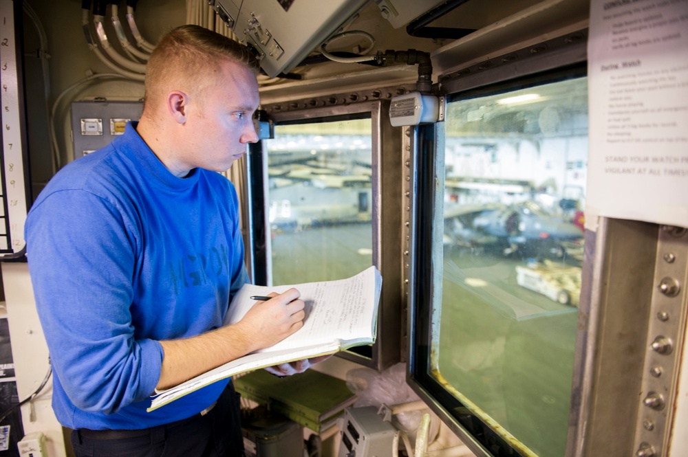 USS America Sailor stands hangar bay watch